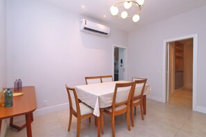 A dining area with a table set for four, a ceiling fan, and an air conditioning unit. - D055 (Rio de Janeiro)
