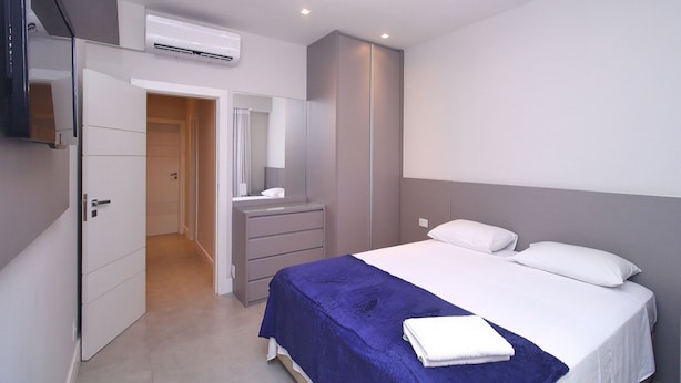 A modern bedroom with a bed, a dresser, and a mirror. - D055 (Rio de Janeiro)