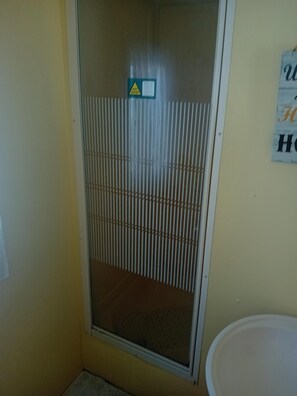 Un baño con ducha, toallero y un cartel en la pared.