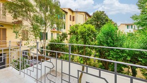 A balcony with a metal railing overlooking a courtyard with trees and buildings. - Silvy & Paul apartment by MMega (Florence)