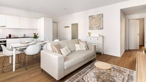 A modern, minimalist living room with a sofa, dining table, and kitchen area. - City Center Luxury with AC & Free Parking (Lugano)