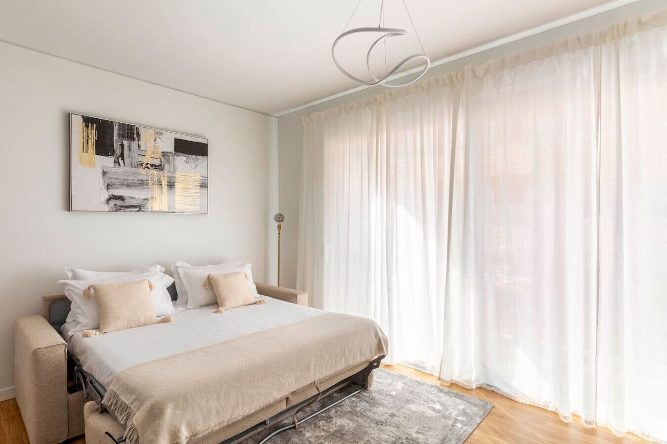 Ein modernes Schlafzimmer mit einem großen Bett, einem Nachttisch, einer Stehlampe und einem großen Fenster mit transparenten Vorhängen.