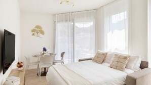 A hotel room with a bed, a desk, and a TV. - Elegant new Apt with AC, private balcony & garage (Viganello)