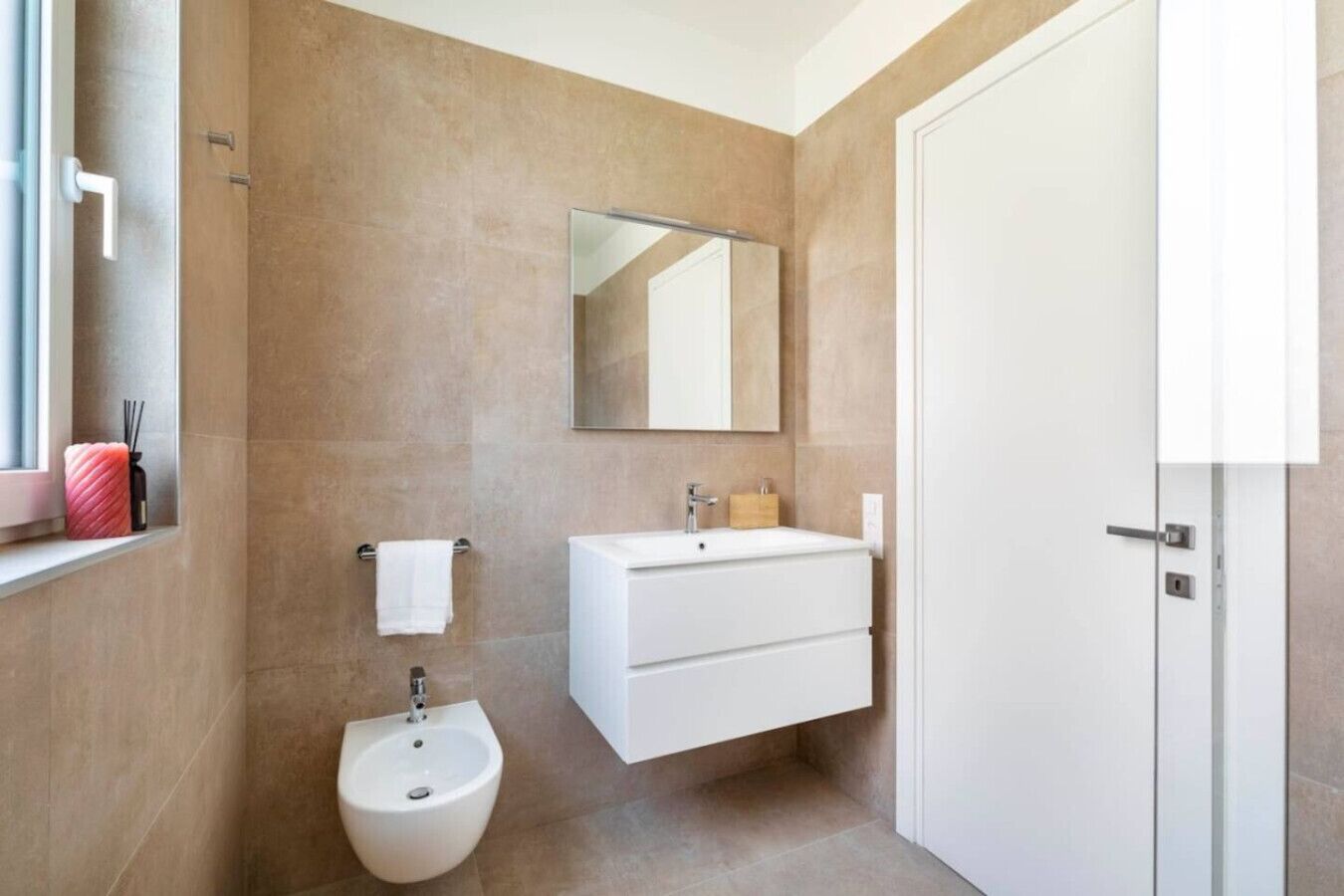 A modern bathroom with a bidet, a sink, and a mirror.