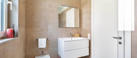 A modern bathroom with a bidet, a sink, and a mirror.