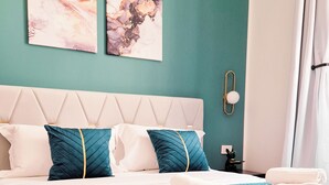 A neatly made bed with a teal striped bedspread, two pillows, and a folded white towel on the side. - Ginevra Suite (Bologna)