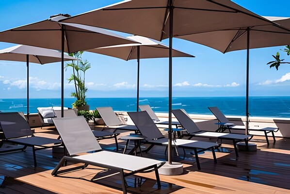A deck with sun loungers and umbrellas overlooking the ocean. - 1 BR Golden Zone · Luxury Beach and Infinity Pool (Bucerías)