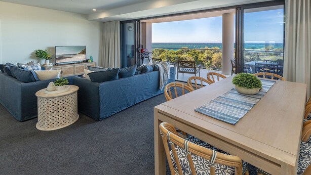 Un salon moderne avec un ensemble de canapés, une table à manger et une vue sur la mer.