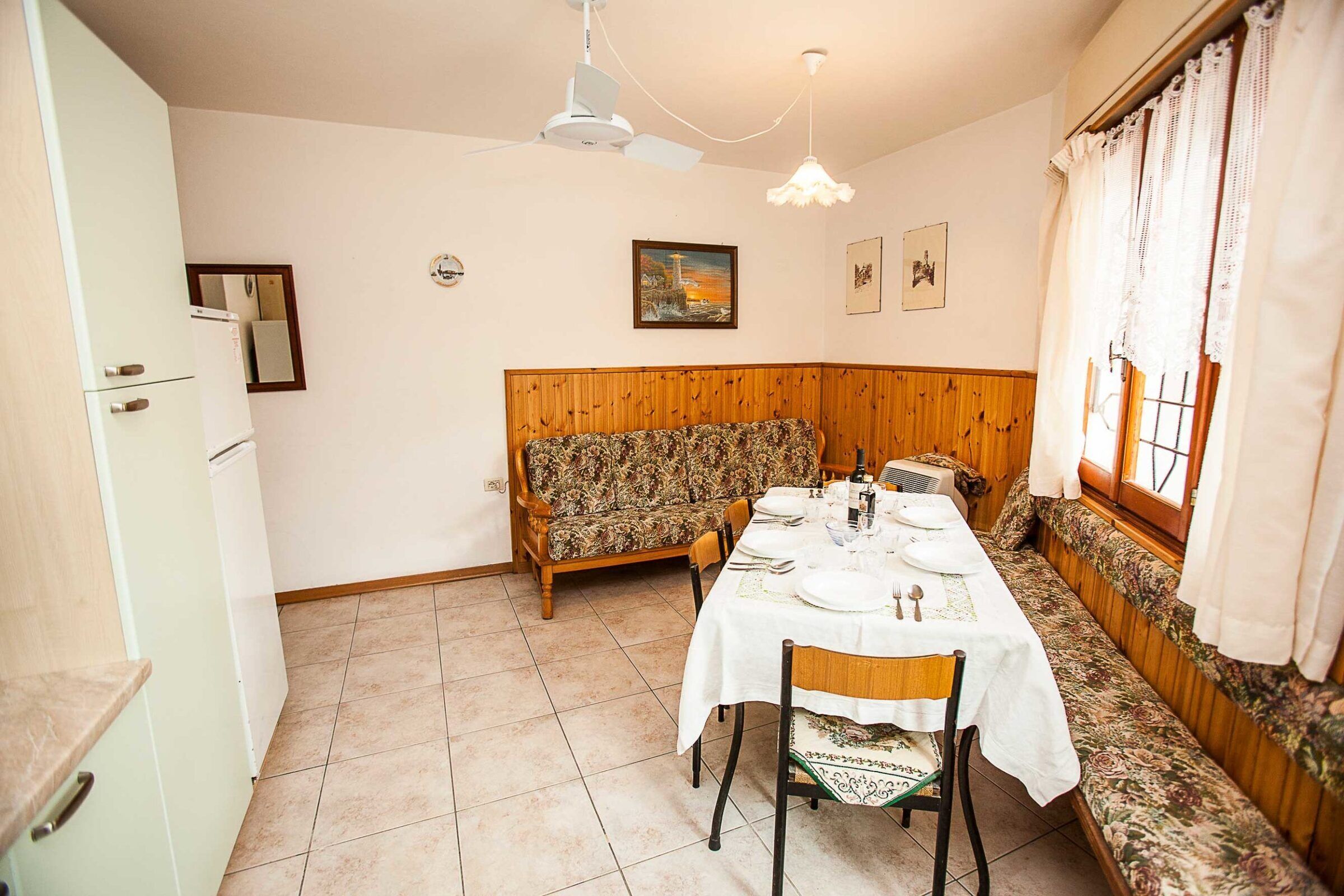 Uma área de refeições com um banco de madeira e uma mesa posta para dois.