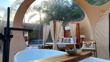 Un accogliente alloggio in tenda con un letto, una zona salotto e una vasca da bagno.