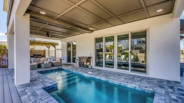 Ein moderner Poolbereich im Freien mit einer überdachten Terrasse, Sitzgelegenheiten und Blick auf die Umgebung.