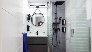 A modern bathroom with a glass shower enclosure, a vanity with a mirror, and a towel rack.