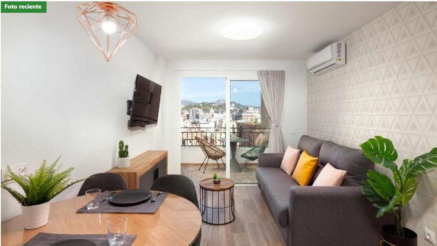 A modern living room with a dining area, a sofa, and a balcony with a city view.