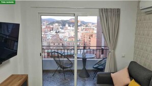 A balcony with a city view, a sofa, a table, and a TV.