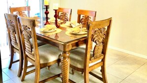 Una sala da pranzo con un tavolo e sedie in legno, un lampadario e un quadro appeso al muro.