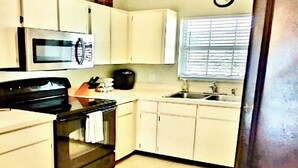 Una cucina compatta con mobili bianchi, un forno a microonde, un forno e un lavandino.
