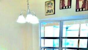 A dining area with a white table and wooden chairs, a hanging light fixture, and a window with a view. - Ref 319. Modern lake view pool home. Very close to Disney (Kissimmee)