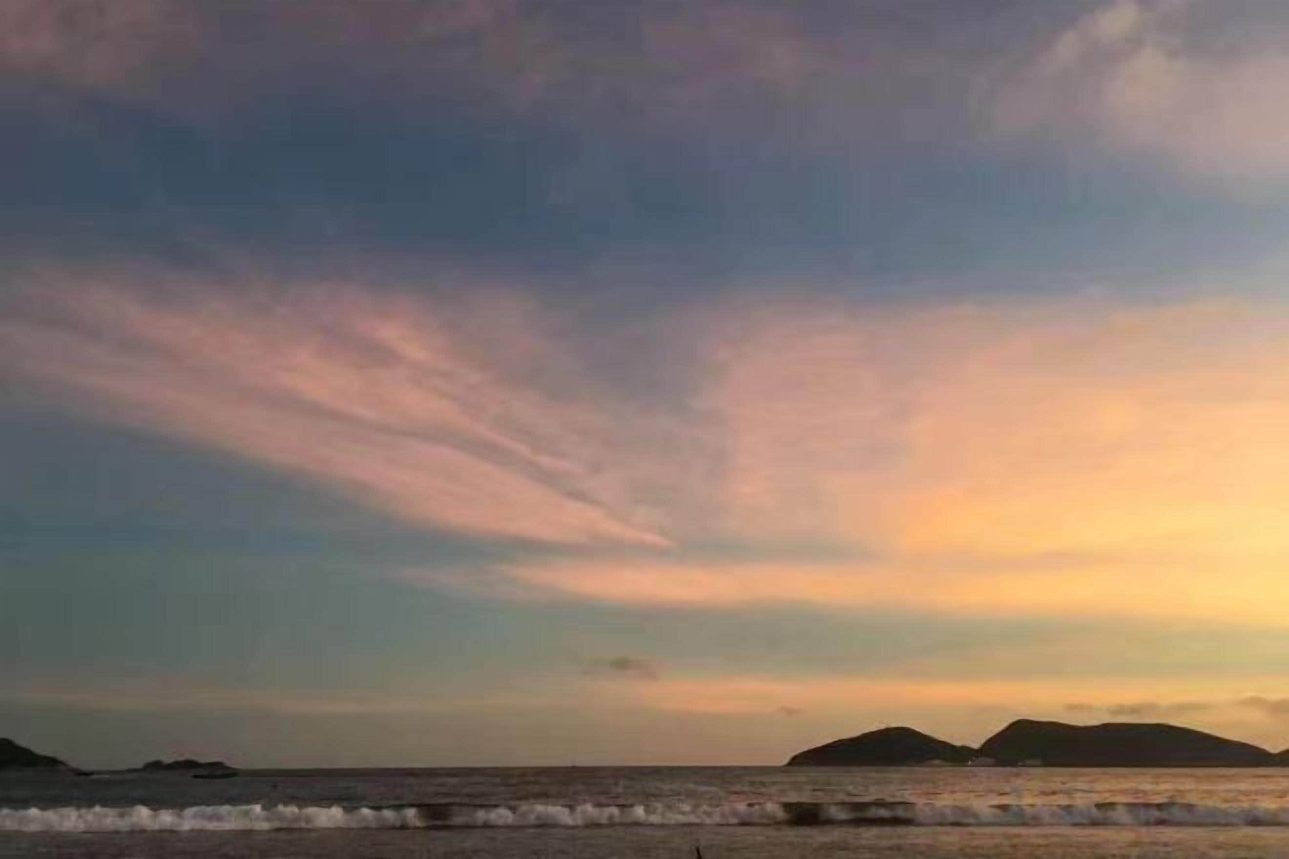 Un paysage côtier avec un ciel dégagé et des reliefs visibles au loin.
