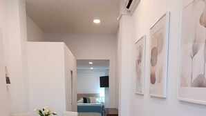 Quarto de hotel moderno com área de refeições, cama e televisão.