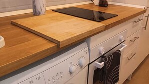Uma cozinha moderna com bancada de madeira, forno embutido, máquina de lavar e cafeteira.