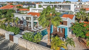 Un quartier résidentiel moderne doté d’une piscine, de palmiers et d’un mur en pierre.