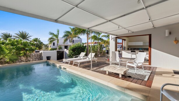Un espace piscine avec une eau claire, entouré de chaises longues et doté d’un patio couvert.