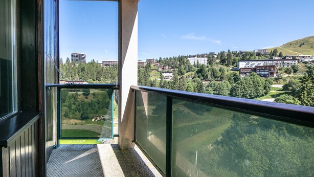 Een balkon met uitzicht op een stad en groen.