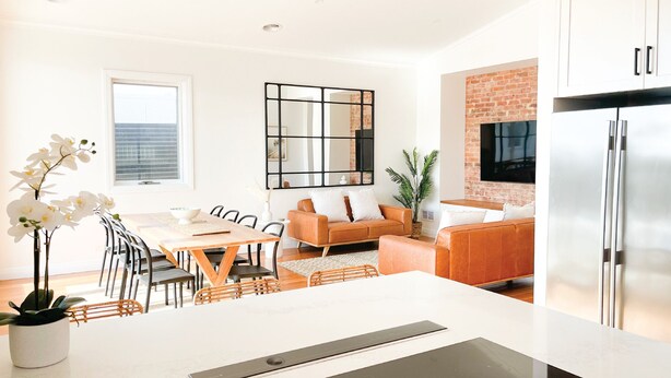 Una cocina moderna con horno empotrado, refrigerador y comedor con mesa y sillas.