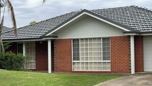 A single-story house with a brick exterior, a large window, and a garage door.