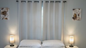Een keurig opgemaakt bed met witte lakens en twee bedlampjes.