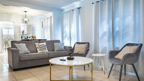 Een moderne woonkamer met een grijze bank, een ronde salontafel en een grijze fauteuil.