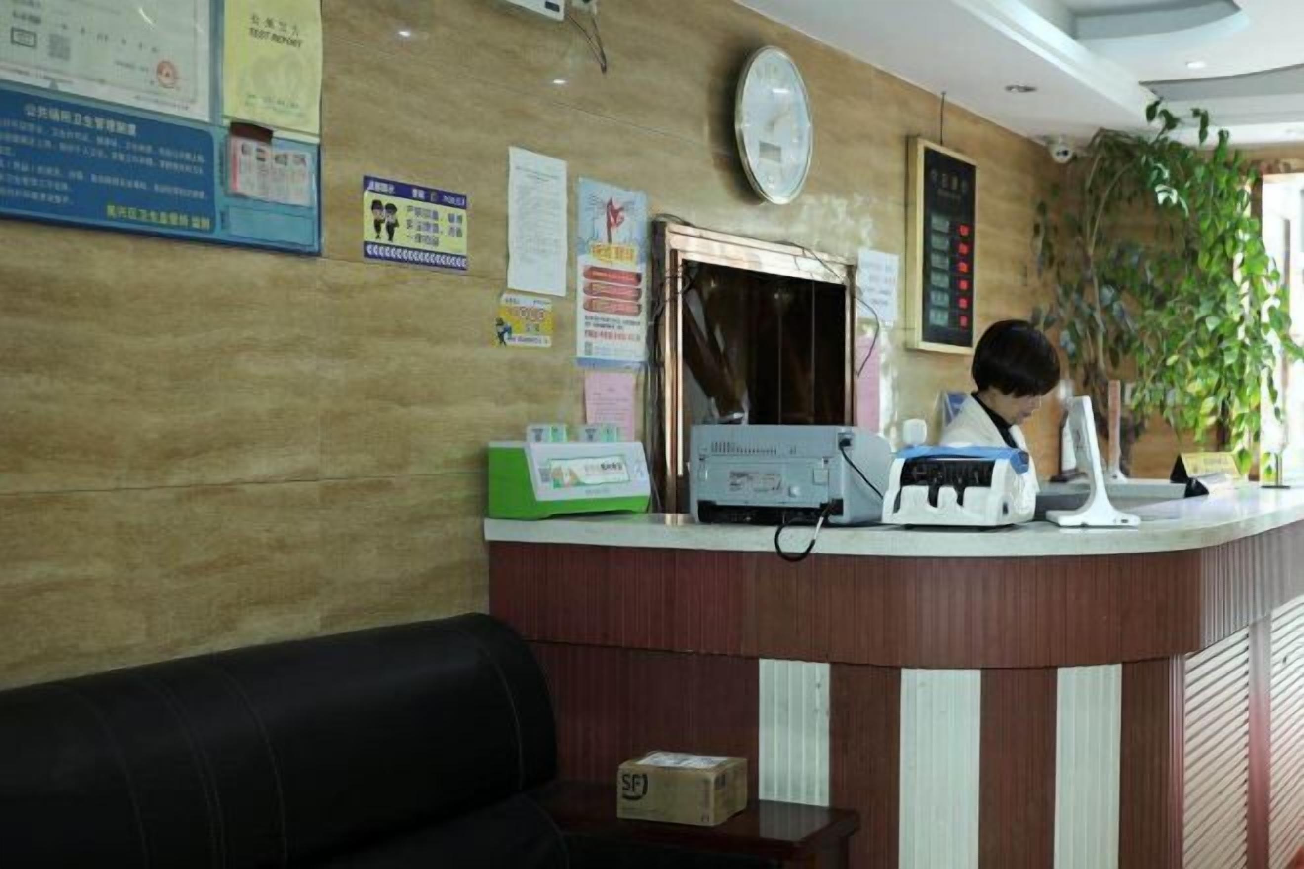 Un área de recepción con un mostrador de madera, un reloj y varios carteles informativos en la pared.