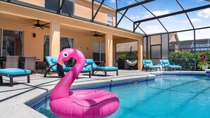 A pool area with lounge chairs, a hanging chair, and a pink flamingo float. - Lovely 7 Bed Pool Home with Game Room-8510PHD (Kissimmee)