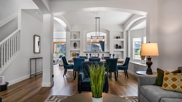 A spacious living room with a dining area, featuring a staircase, a chandelier, and a view of the outdoors. - Lovely 7 Bed Pool Home with Game Room-8510PHD (Kissimmee)