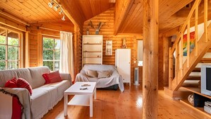 A log cabin interior with a wooden floor, a sofa, a coffee table, a cabinet, and a staircase. - Serene 2-bedroom house with WiFi in Arucas (arucas)