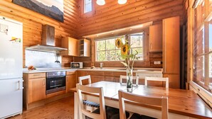 A wooden cabin interior with a kitchen, dining table, and chairs. - Serene 2-bedroom house with WiFi in Arucas (arucas)