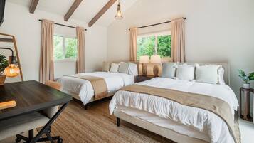 Une chambre avec deux lits, un bureau en bois et une grande fenêtre avec des rideaux.