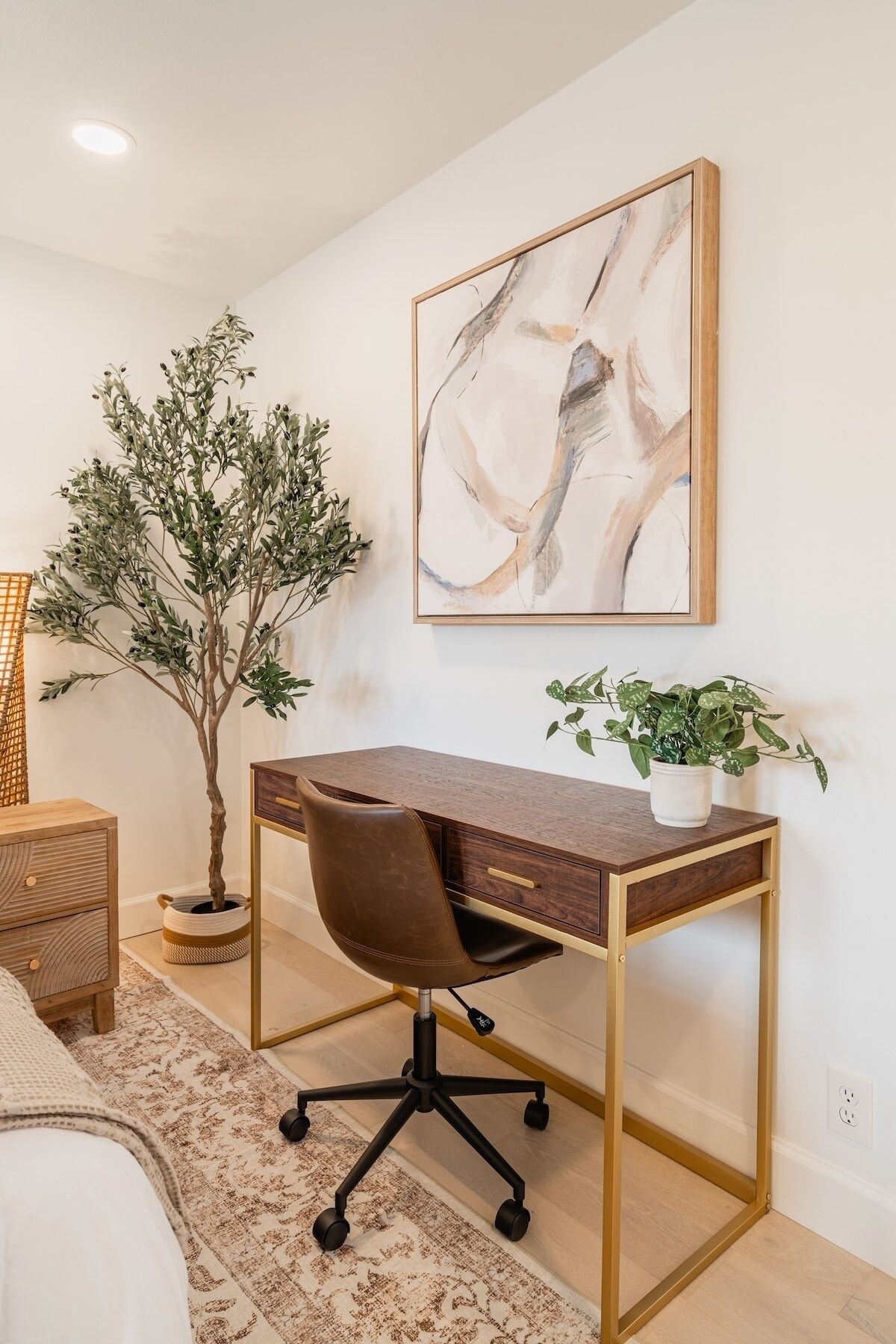 A modern home office with a desk, chair, and a large abstract painting on the wall.