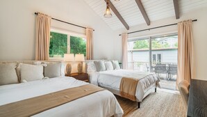 A bedroom with two beds, a large window, and a balcony.