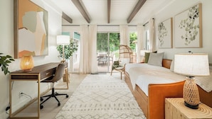 A bedroom with a bed, desk, chair, and a view of the outdoors.
