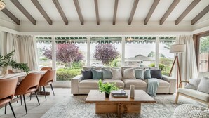 A spacious living room with a large window, a wooden coffee table, and a beige sofa.