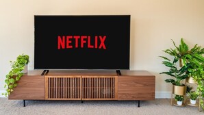 A television on a wooden stand with a black screen displaying "NETFLIX" in red letters.