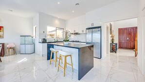 Cozinha moderna com uma ilha grande, banquetas, geladeira e vista para a sala de estar.
