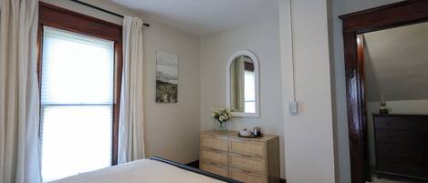 A bedroom with a bed, a dresser, a mirror, and a ceiling fan.