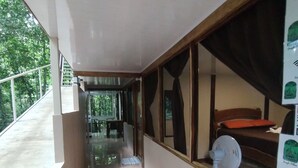 A corridor with a tiled floor, a window with a curtain, and a fan on the right. - Cool Waters Jungle Camping (Bahía Ballena)