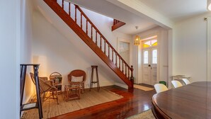 A dining area with a wooden staircase, wicker chairs, a dining table, and a rug. - FLH Funchal Casa do Carvalhal (Funchal)