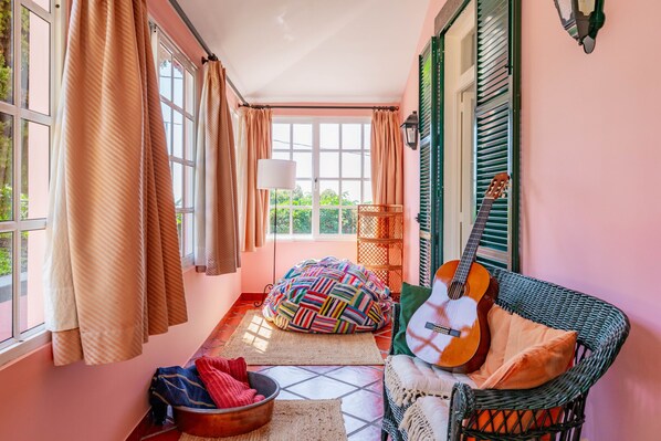 A cozy room with a wicker sofa, colorful bean bag, and a guitar.