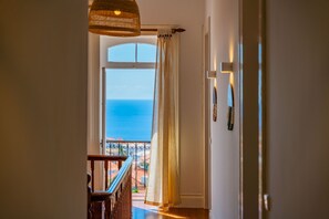 A hallway leading to a balcony with a view of the sea.