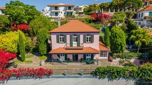 A two-story house with a red-tiled roof, a balcony, and a garden with various plants and flowers. - FLH Funchal Casa do Carvalhal (Funchal)