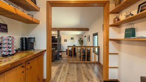 A wooden interior with a kitchen area, wooden shelves, and a dining area.